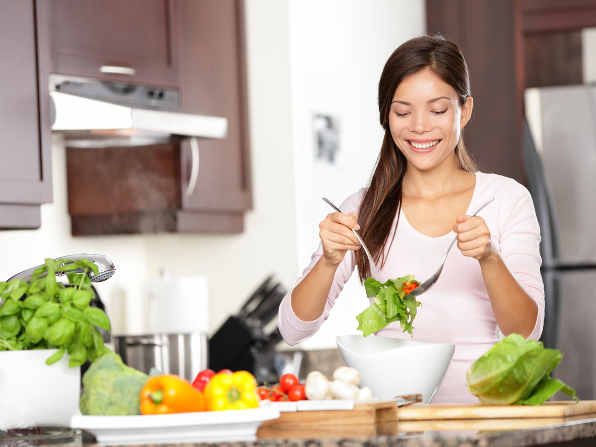 Woman making salad in kitchen. Healthy eating lifestyle concept with beautiful young woman cooking in her kitchen. See more: