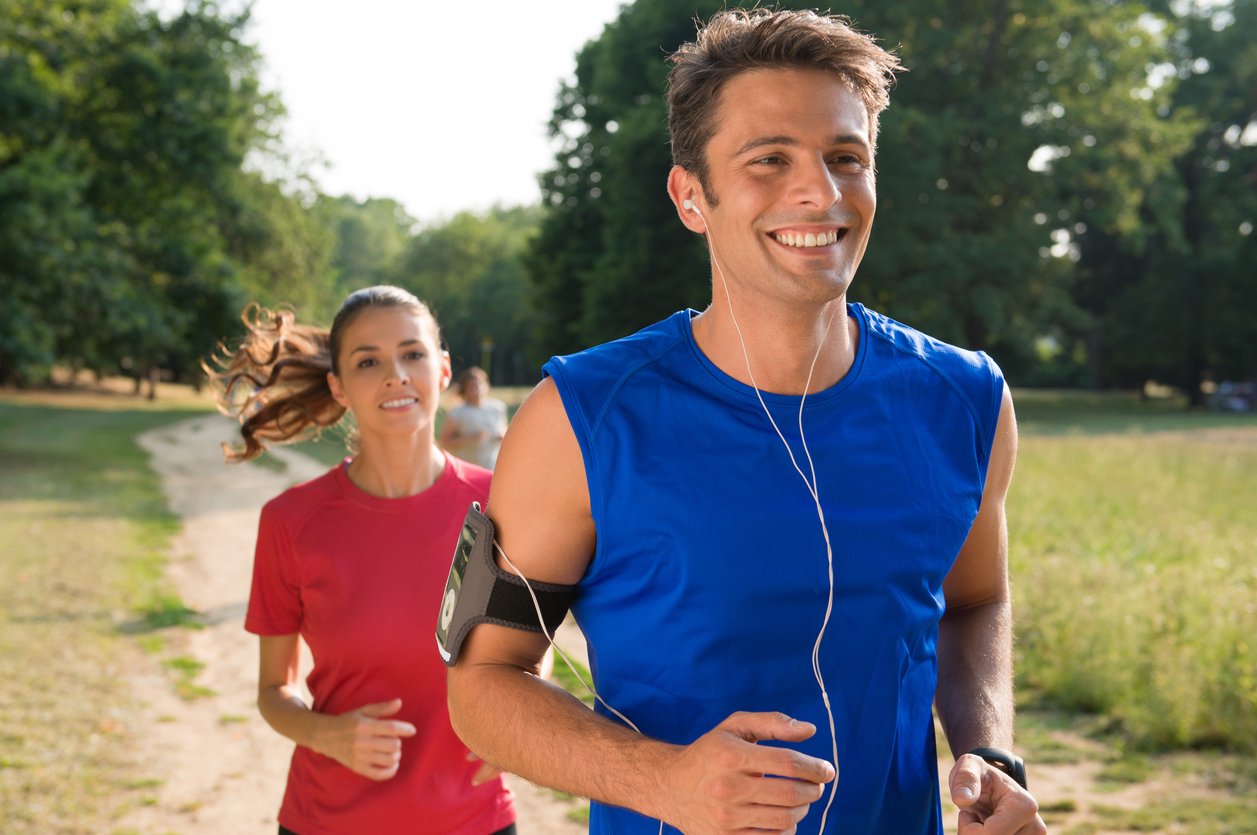Young Man Listening To Music While Jogging With Woman.