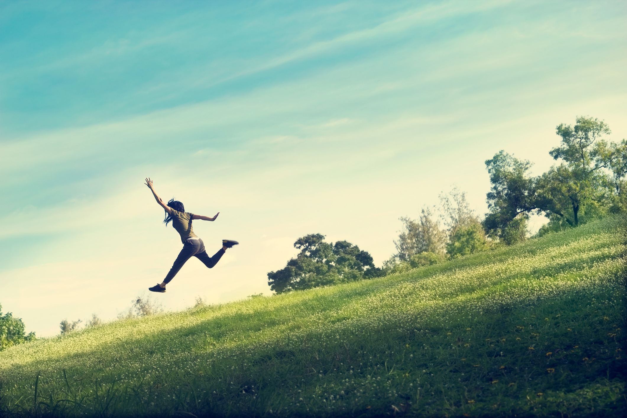 woman running and jumping funny relax on green grass and flower field